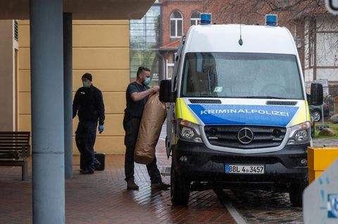 Ein Mitarbeiter der Kriminalpolizei bringt Gegenstände auf dem Gelände eines Potsdamer Wohnheimes in ein Polizeiauto. In dem Wohnheim sind vier Leichen gefunden worden. 