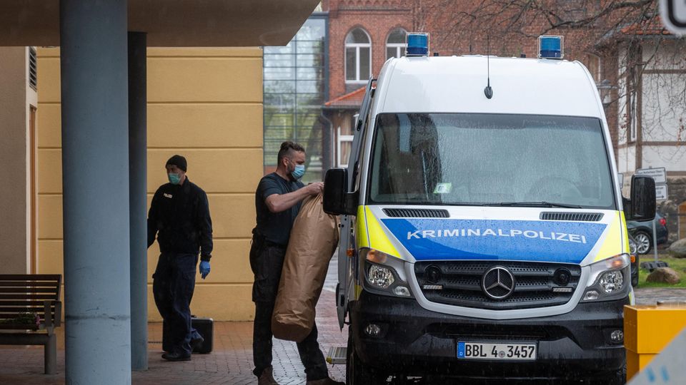 Ein Mitarbeiter der Kriminalpolizei bringt Gegenstände auf dem Gelände eines Potsdamer Wohnheimes in ein Polizeiauto. In dem Wohnheim sind vier Leichen gefunden worden. 