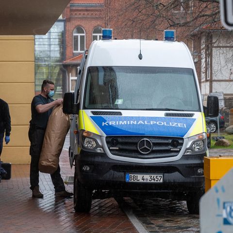 Ein Mitarbeiter der Kriminalpolizei bringt Gegenstände auf dem Gelände eines Potsdamer Wohnheimes in ein Polizeiauto. In dem Wohnheim sind vier Leichen gefunden worden. 