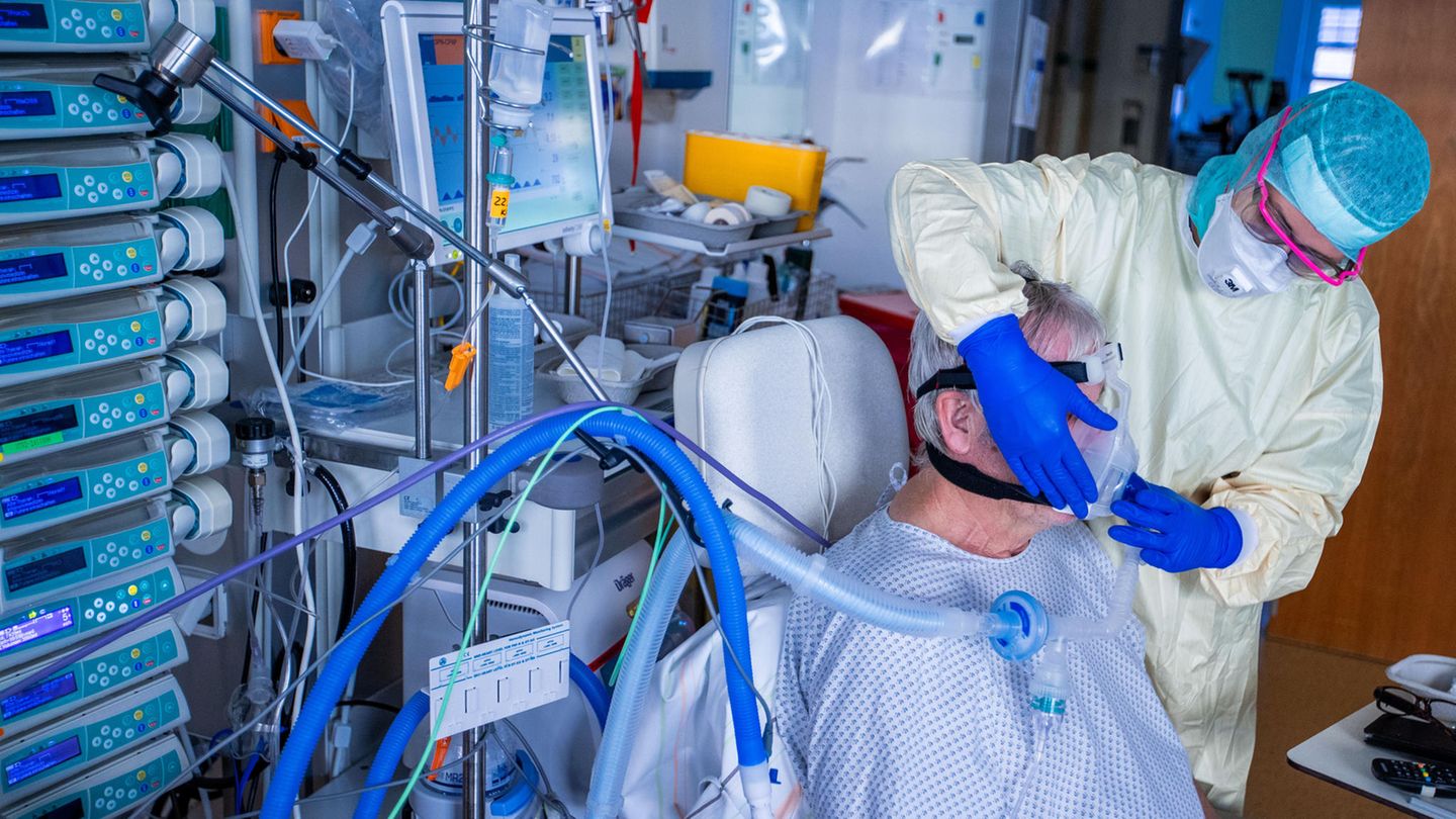 Eine Krankenpflegerin setzt einem Patienten eine Beatmungsmaske auf. Eine Krankenpflegerin setzt einem Patienten eine Beatmungsmaske auf.