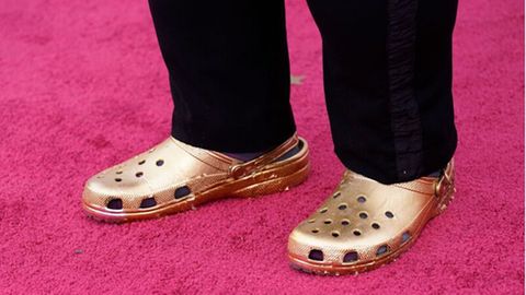 Ein Paar goldener Crocs auf dem roten Teppich der Oscars