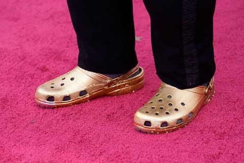 Ein Paar goldener Crocs auf dem roten Teppich der Oscars