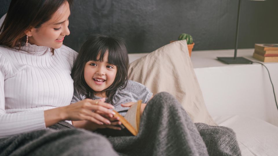 Mutter und Tochter kuscheln auf dem Bett