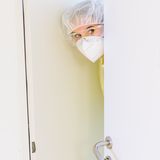 Eine Pflegerin mit Maske und Schutzbrille schaut aus einem Krankenzimmer heraus