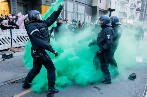 Polizisten versuchen beim Demonstrationszug linker und linksradikaler Gruppen Pyrotechnik zu beseitigen