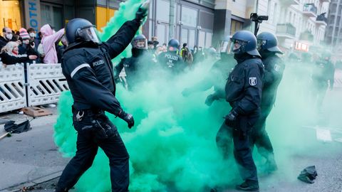 Polizisten versuchen beim Demonstrationszug linker und linksradikaler Gruppen Pyrotechnik zu beseitigen