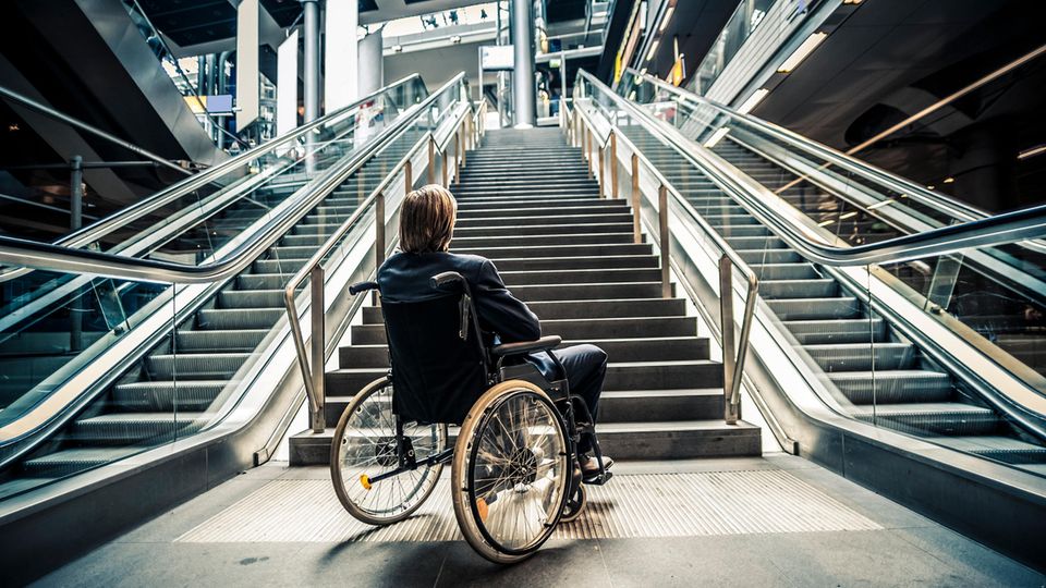 Ein Mann in einem Rollstuhl steht vor einer Treppe