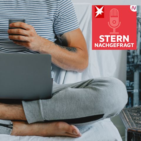 Mann sitzt in Jogginghose und mit Laptop im Bett