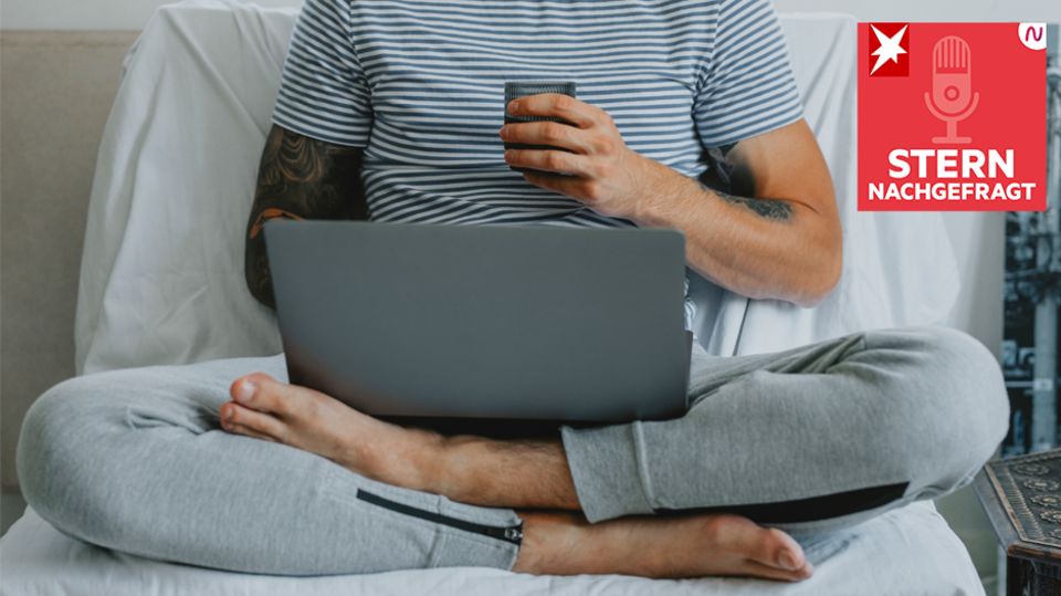 Mann sitzt in Jogginghose und mit Laptop im Bett