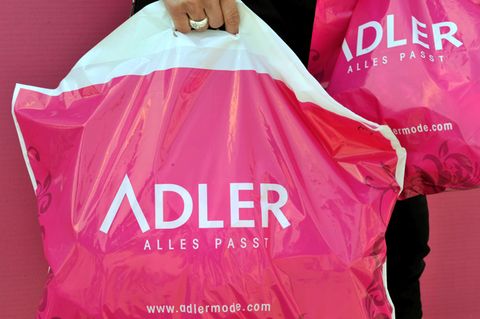 Eine Hand trägt eine Plastiktüte der Textil-Einzelhandelskette Adler Modemärkte