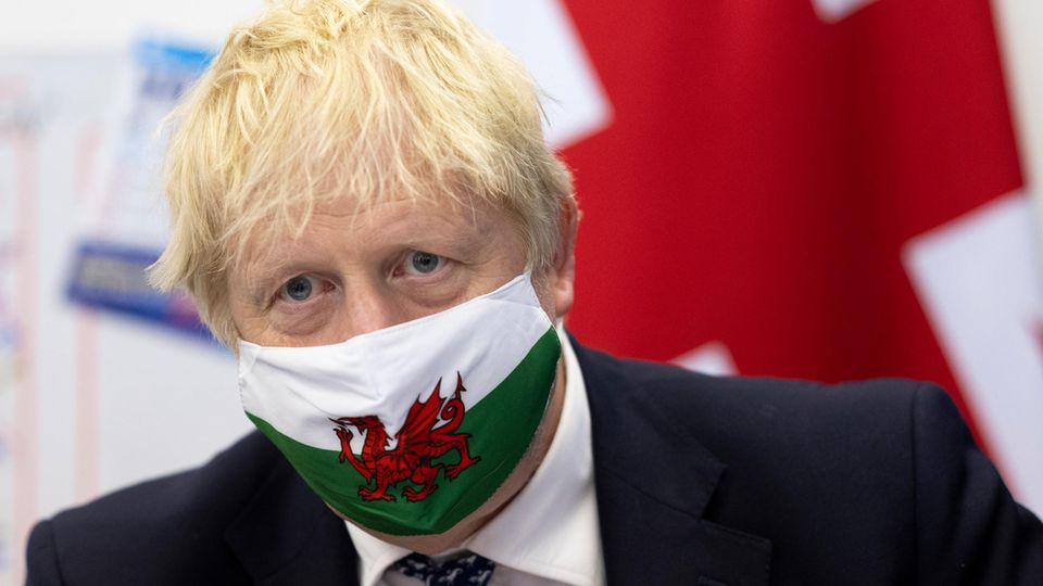 Boris Johnson trägt eine Gesichtsmaske mit der walisischen Flagge