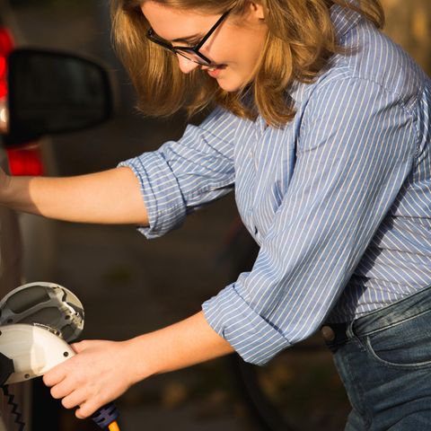 Frau lädt ihr E-Auto an einer Ladestation.