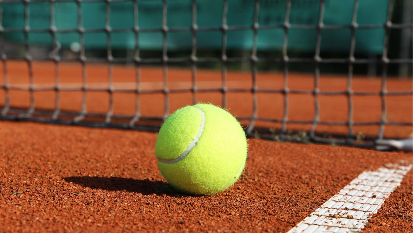 Tennisball liegt vor einem Netz.