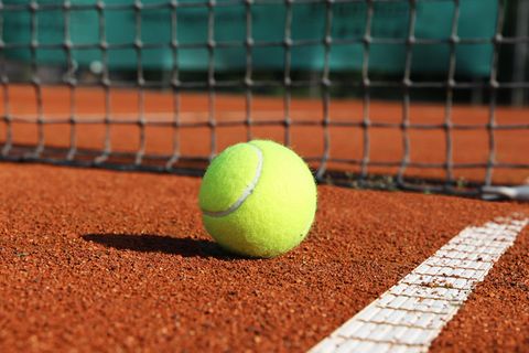 Tennisball liegt vor einem Netz.