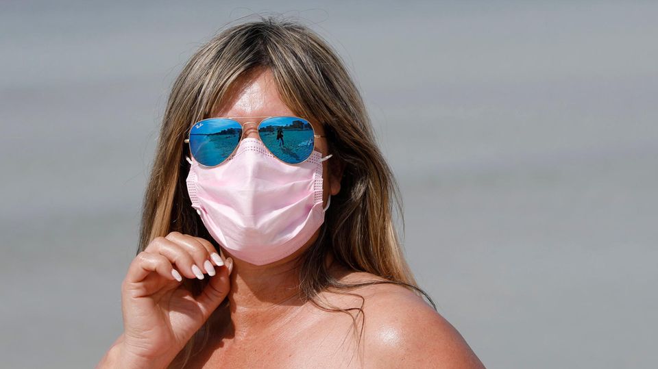 Urlauberin am Strand in Spanien Eine dunkelblonde weiße Frau steht an einem Strand in der Sonne. Sie trägt eine blau verspiegelte Pilotenbrille sowie eine Maske