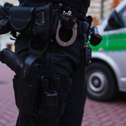Ein Polizeibeamter steht neben seinem Einsatzfahrzeug
