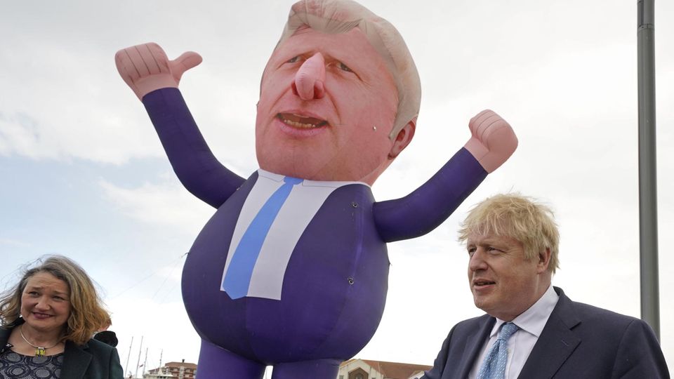 Boris Johnson und Jill Mortimer stehen neben einer über 9 Meter großen aufblasbaren Figur des Premiers