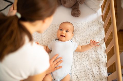 Mutter beugt sich über Krippe mit Baby