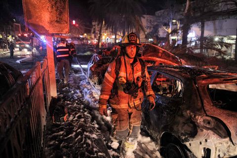 Feuerwehrmann geht durch Zerstörungen durch einen Raketneinschlag nahe Tel Aviv