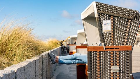 Schleswig-Holstein, Wenningstedt: Eine Frau sitzt auf der Besucherpromenade in einem Strandkorb