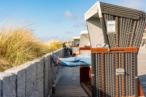 Schleswig-Holstein, Wenningstedt: Eine Frau sitzt auf der Besucherpromenade in einem Strandkorb
