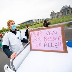 Ein Teilnehmer der Aktion "Der Pflege geht die Luft aus" geht mit einem Krankenhausbett am Reichstagsgebäude vorbei