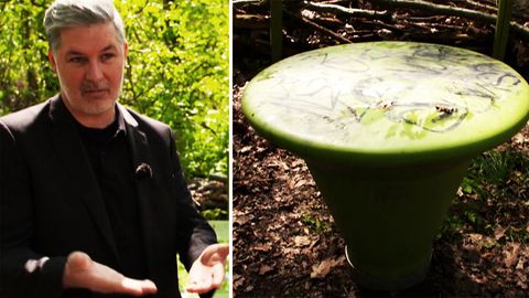 Mann stehet neben grünen Plastikmöbeln in einem Park