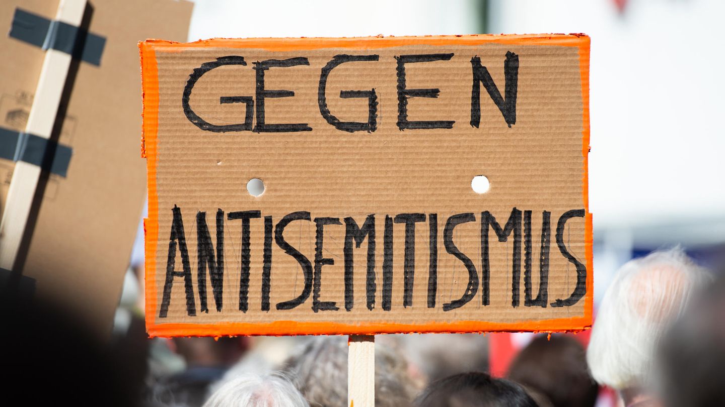 Ein Person hält bei einer Kundgebung ein Plakat mit der Aufschrift "Gegen Antisemitismus" in die Höhe