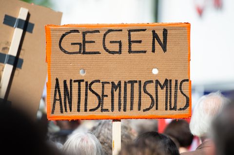 Ein Person hält bei einer Kundgebung ein Plakat mit der Aufschrift "Gegen Antisemitismus" in die Höhe