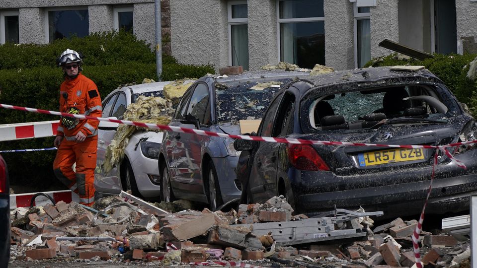 Zerstörte Autos Einsatzkräfte stehen vor einer Reihe zerstörter Autos
