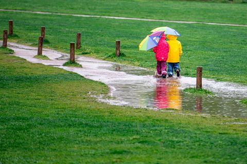 Zwei Kinder spazieren im Regen
