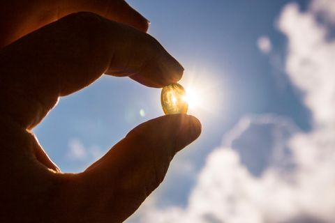 Vitamin D und Corona: eine Frau hält eine Vitamin D-Tablette in der Hand