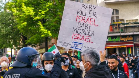 Demonstranten halten in Berlin ein Schild "Babymörder Israel"