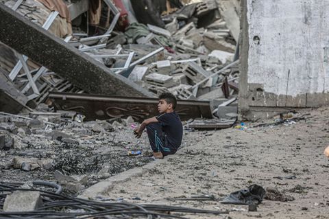 Ein Junge sitzt vor den Trümmern eines eingestürzten Wohnhauses, nachdem es von einem israelischen Luftangriff getroffen wurde
