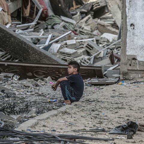 Ein Junge sitzt vor den Trümmern eines eingestürzten Wohnhauses, nachdem es von einem israelischen Luftangriff getroffen wurde