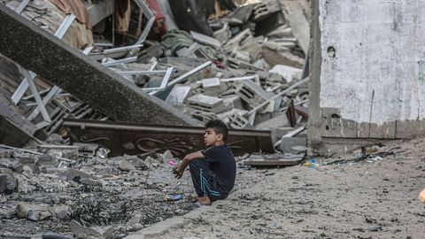 Ein Junge sitzt vor den Trümmern eines eingestürzten Wohnhauses, nachdem es von einem israelischen Luftangriff getroffen wurde