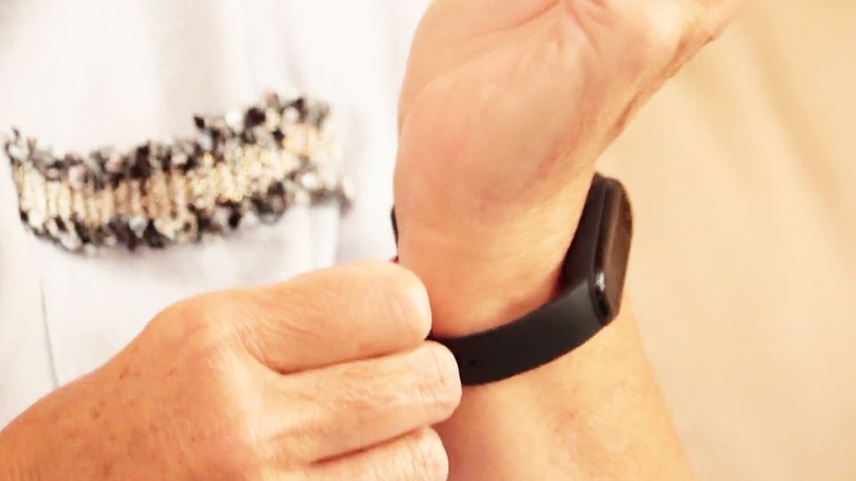 Fitnessgadgets im Test: Tracker, Waage und smarte Trinkflasche Person legt Fitnesstracker an das Handgelenk an