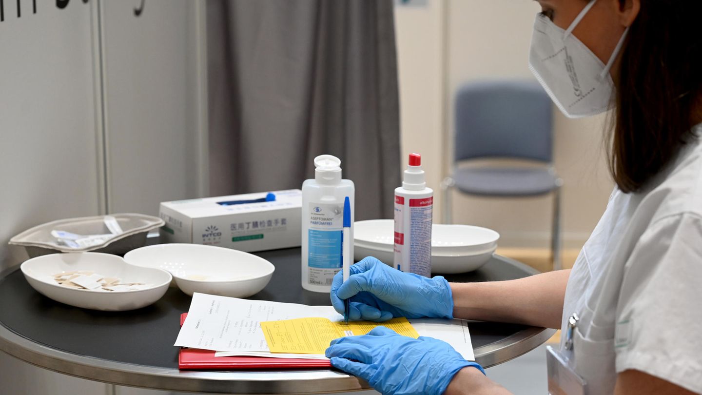 Ärztin füllt einen Impfpass als Impfbescheinigung aus