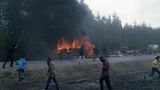Ein Mannschaftswagen der Polizei brennt, davor laufen vermummte Demonstranten umher