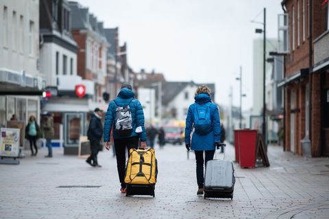 Urlauber gehen mit ihren Koffern durch die Fußgängerzone in Richtung Bahnhof