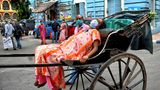 Indien, Kolkata: Eine an Covid-19 erkrankte Frau wird auf einer Rikscha zum Krankenhaus gebracht