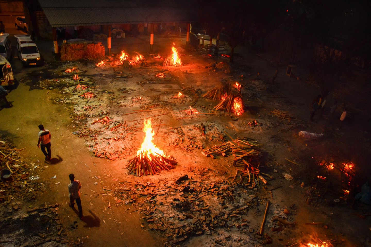 Vielerorts ist die Lage in dem 1,3-Milliarden-Einwohner-Land längst außer Kontrolle. Hier in Neu Delhi lodern Holzfeuer auf dem Gelände eines Krematoriums, in dem Opfer einer Covid-19 Erkrankung verbrannt werden.