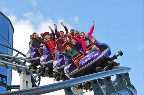 Menschen fahren mit einer Achterbahn und strecken die Hände in de Höhe