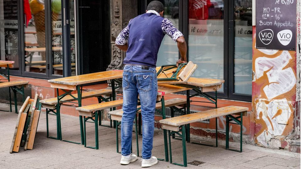 An employee of a restaurant sets up tables and benches in Hamburg's Schanzenviertel