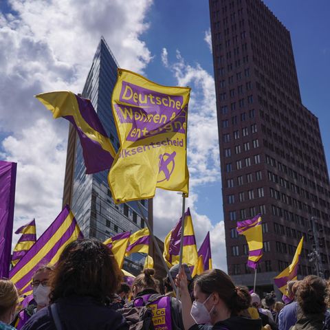 Bei einer Demonstration gegen steigende Mieten halten Teilnehmer Fahnen der Initiative "Deutsche Wohnen & Co. enteignen" in die Höhe