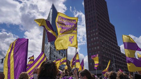 Bei einer Demonstration gegen steigende Mieten halten Teilnehmer Fahnen der Initiative "Deutsche Wohnen & Co. enteignen" in die Höhe