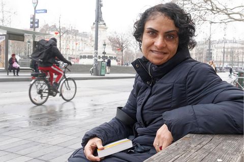 Nadia Ghulam sitzt mit einem Buch in der Hand auf einer Parkbank
