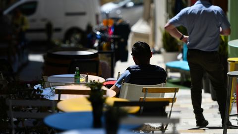 Menschen sitzen bei Sonne in einem Straßencafé