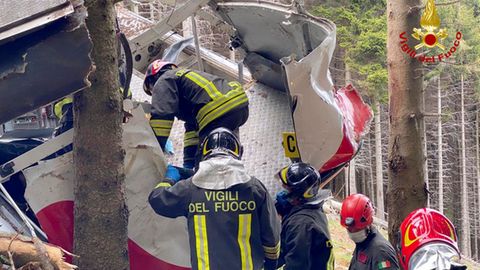 Feuerwehrmänner inspizieren die zerstörte Gondel