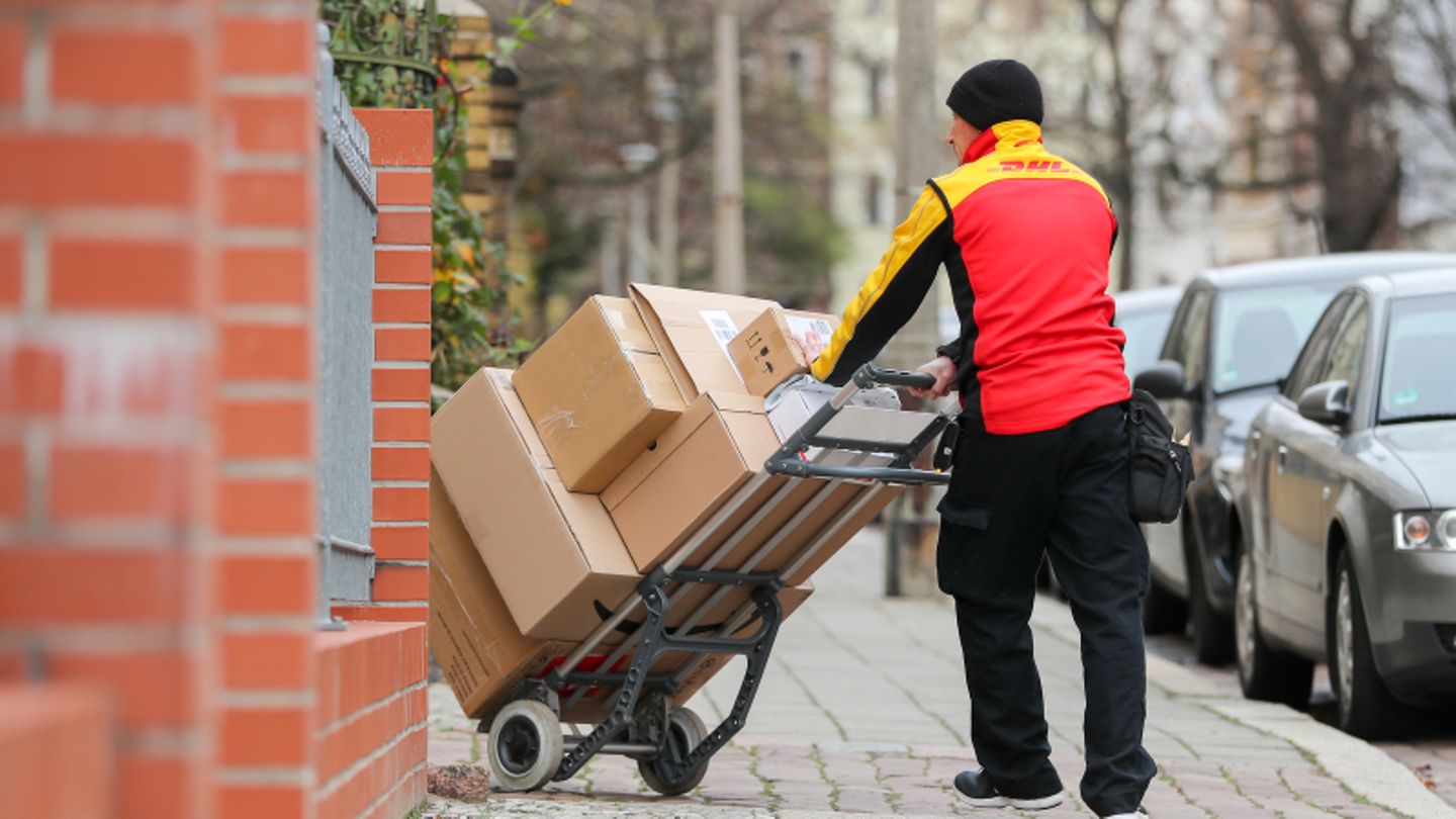 DHL-Zusteller mit einer Sackkarre voller Pakete.
